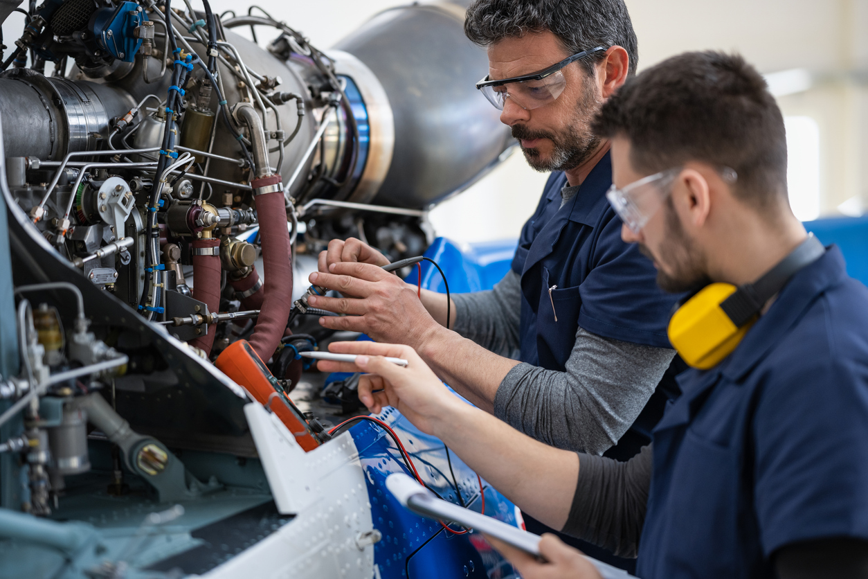 Two Aircraft engineers and mechanics in the hangar repairing and maintaining private helicopter.